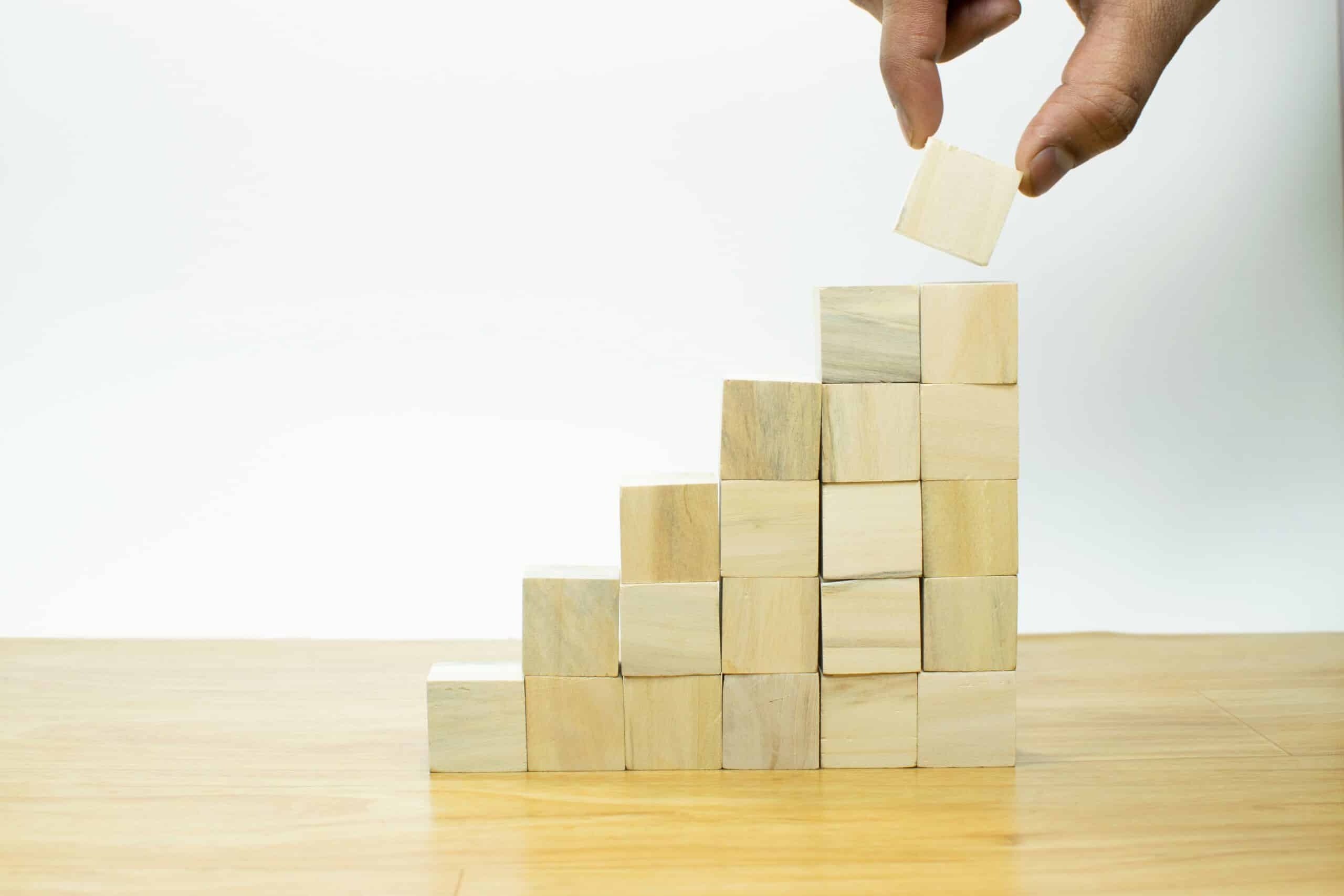 What is the role of AI in building scalable marketing? 1 A hand stacking small wooden blocks into a staircase, representing scalable marketing