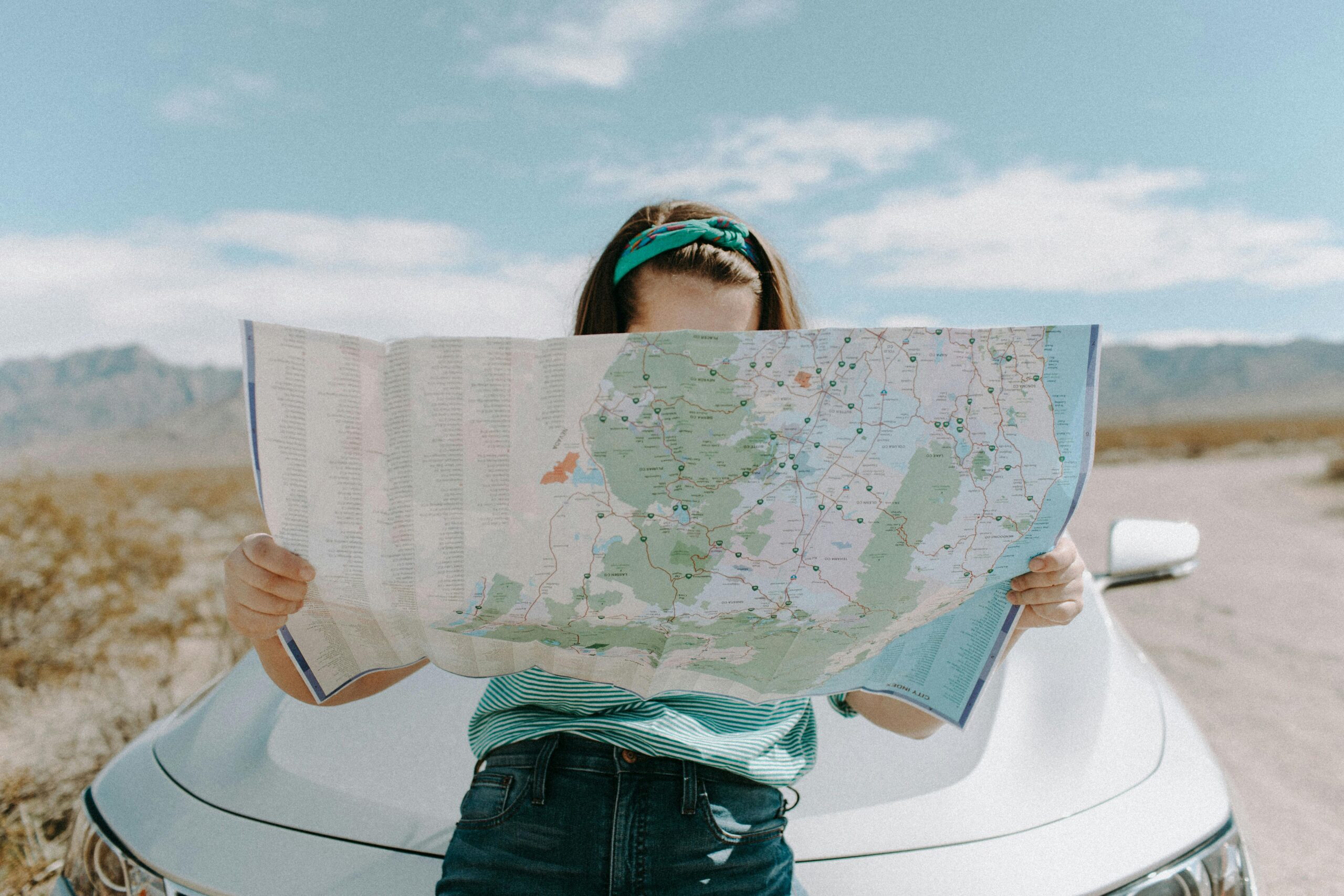 Local SEO for law firms: Why local search engine optimization matters 1 A woman sitting on the hood of a car, looking at a map. Represents local SEO for law firms.