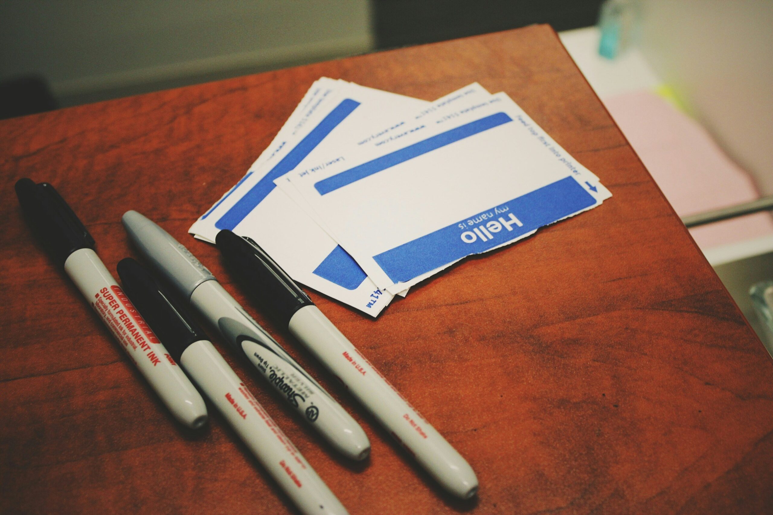 When was the last time you read your attorney bio page? 1 Photograph of a pile of "Hello, my name is" name tags and markers on a wooden table.