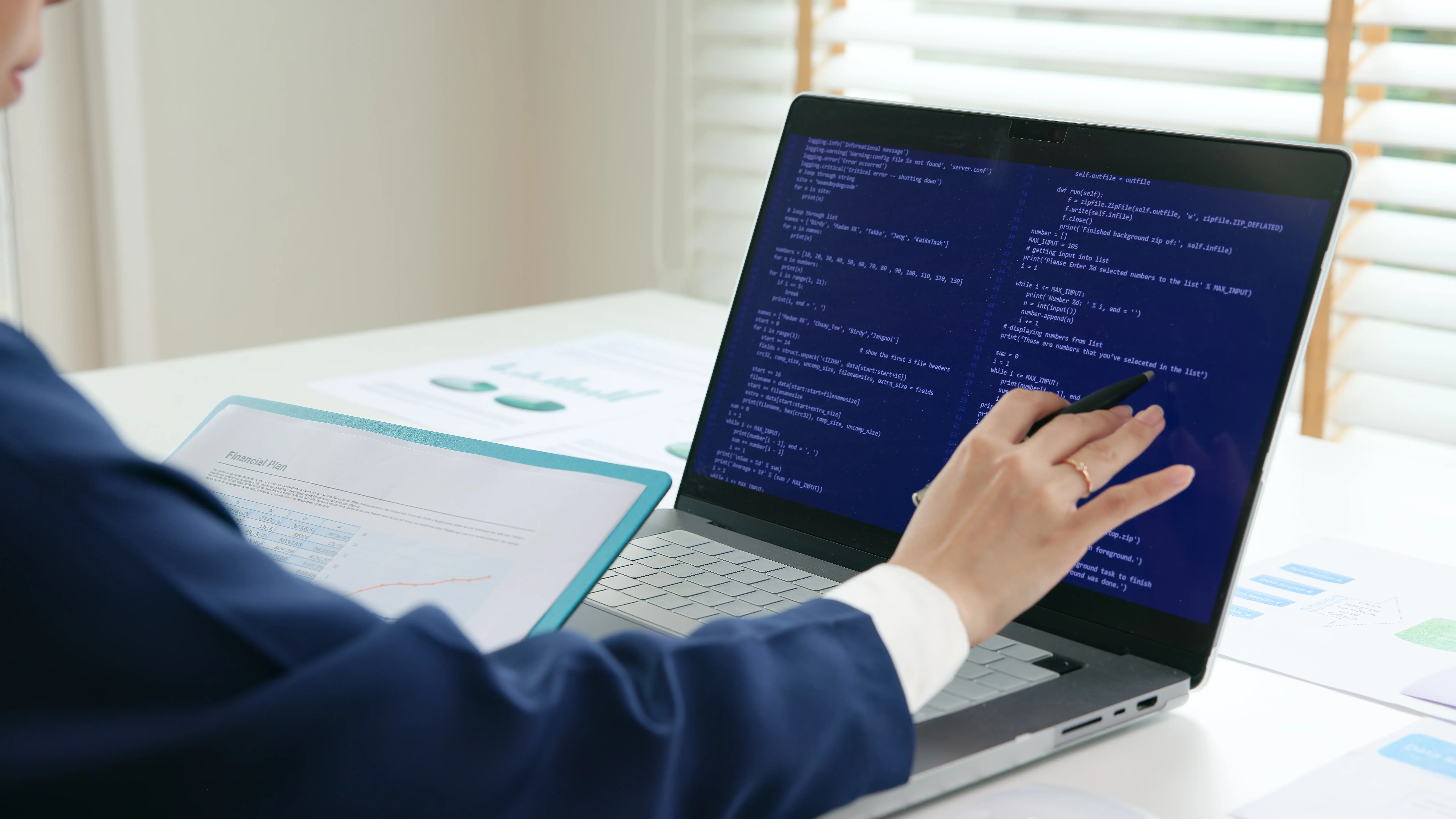 You Can Build an AI-Enabled Device for Your Company, and For Cheap 2 Analyst reviewing code on a laptop next to a printed financial plan report